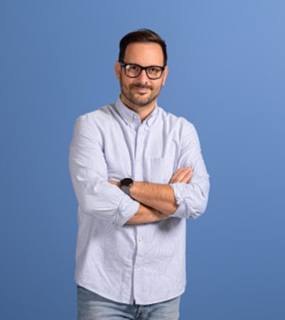 Portrait of confident male professional manager with arms crossed posing on isolated blue background